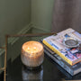 Candle in a decorative holder on a table with books in the background