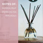 Glass diffuser bottle with reeds on a wooden surface, with text indicating fragrance notes.