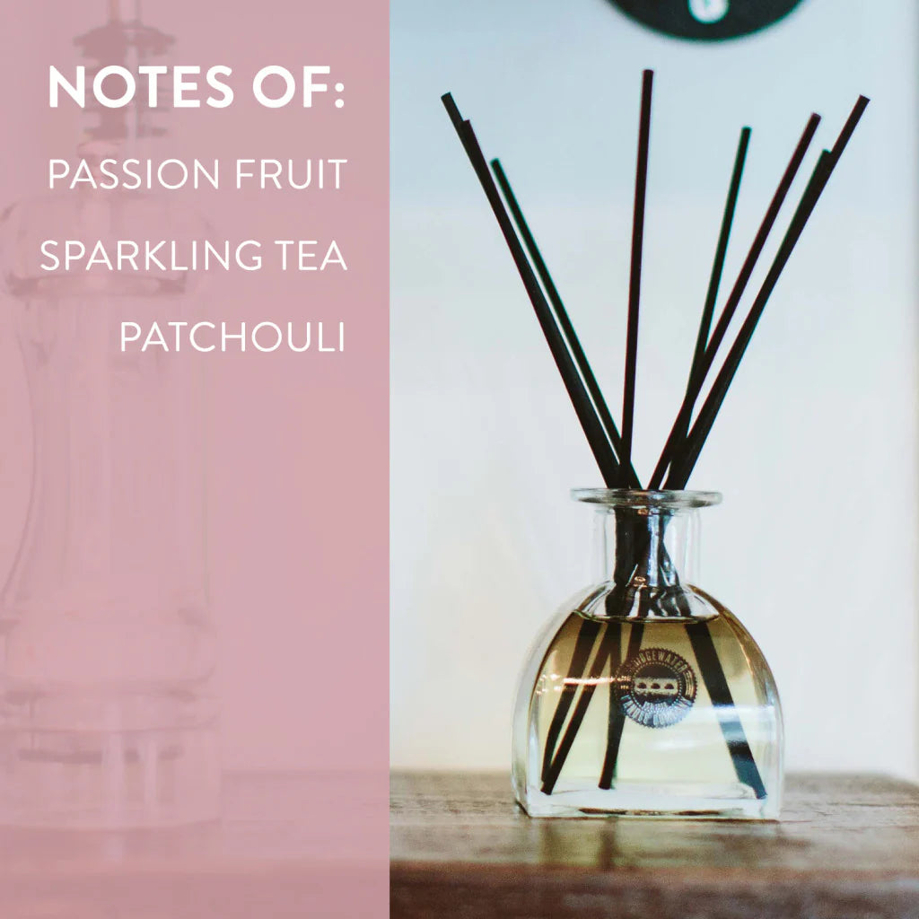 Glass diffuser bottle with reeds on a wooden surface, with text indicating fragrance notes.