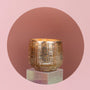 Gold textured candle holder on a pink background