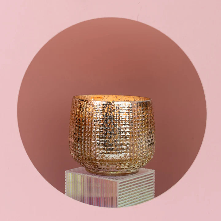 Gold textured candle holder on a pink background