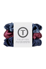 A set of three Teleties hair scrunchies in navy blue, dusty blue, and burgundy, wrapped together with a white paper label featuring the Teleties logo.