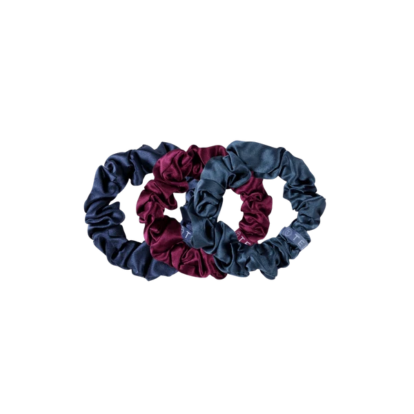 Two velvet fabric scrunchies, one in navy blue and one in burgundy, overlapping on a solid white background.