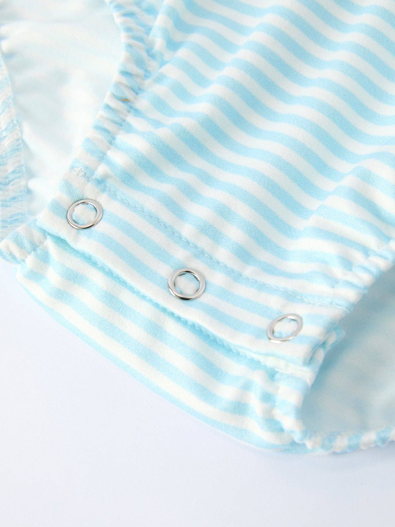 Close-up of a baby romper with blue and white stripes on a light gray background