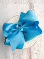 Blue bow on a white plate with a light wooden background