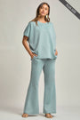 Woman wearing a light blue outfit with wide-leg pants on a plain background