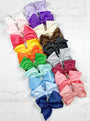 Assorted colorful hair bows on a light wooden surface