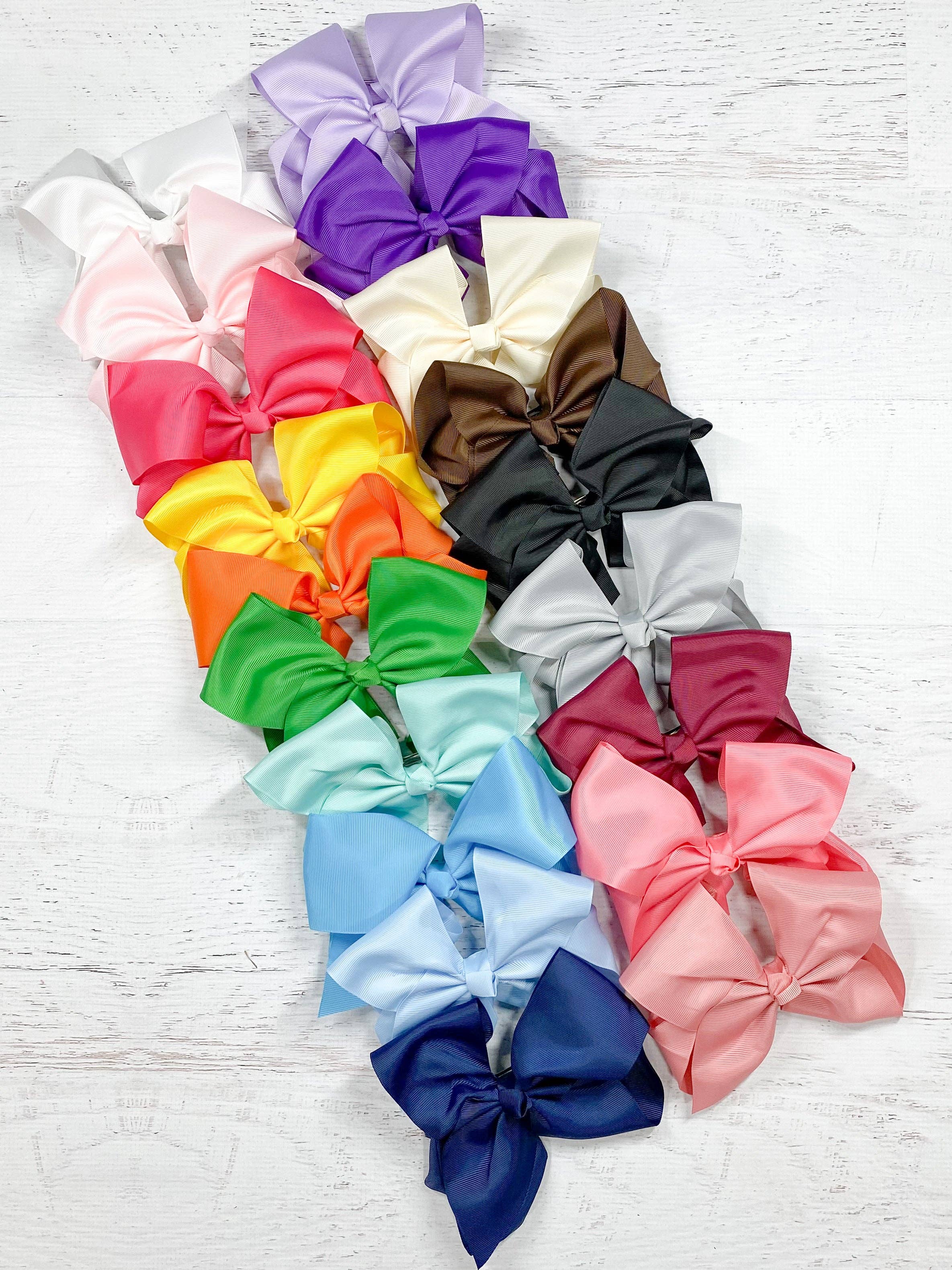 Assorted colorful hair bows on a light wooden surface