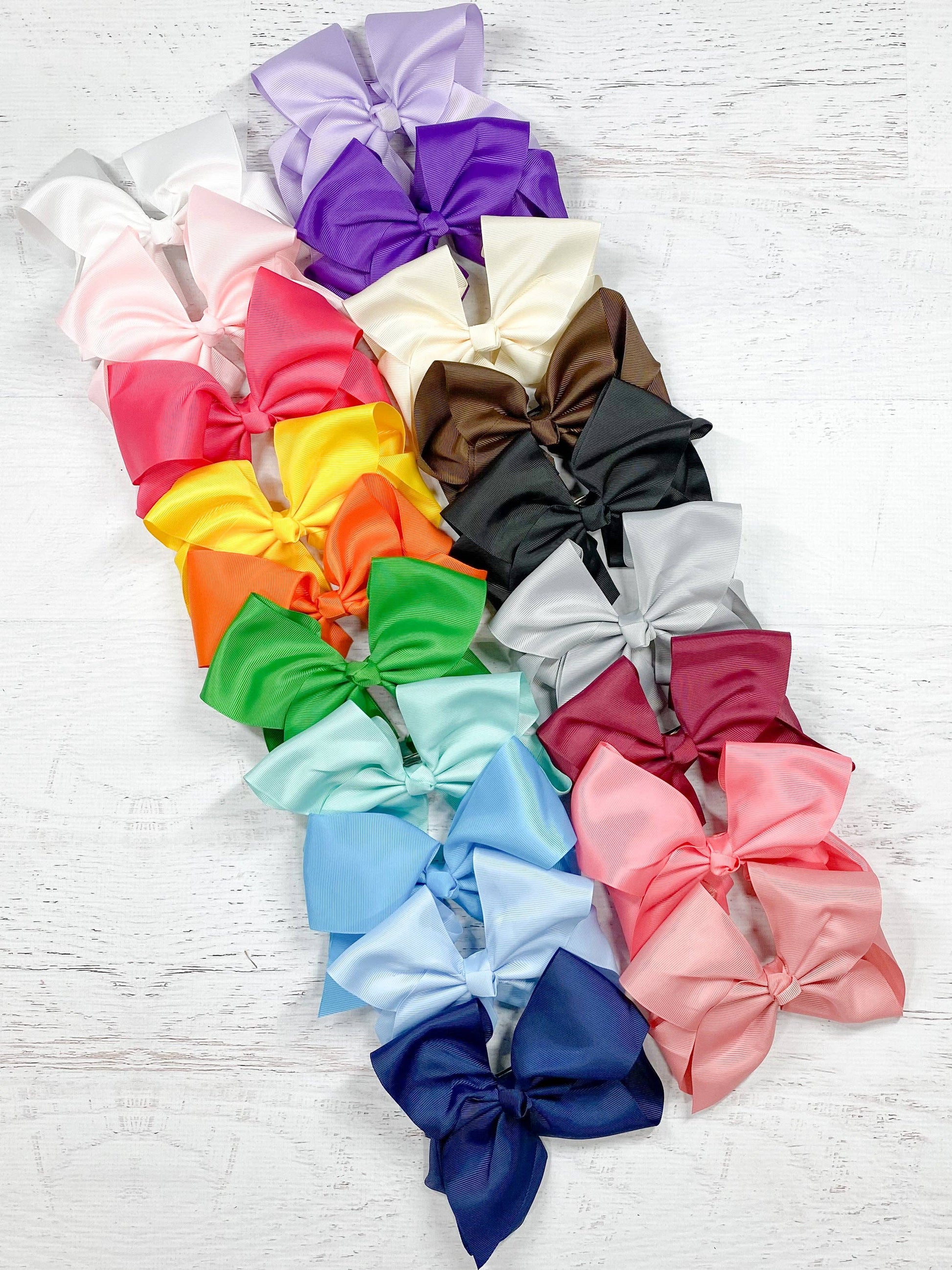 Assorted colorful hair bows on a light wooden surface