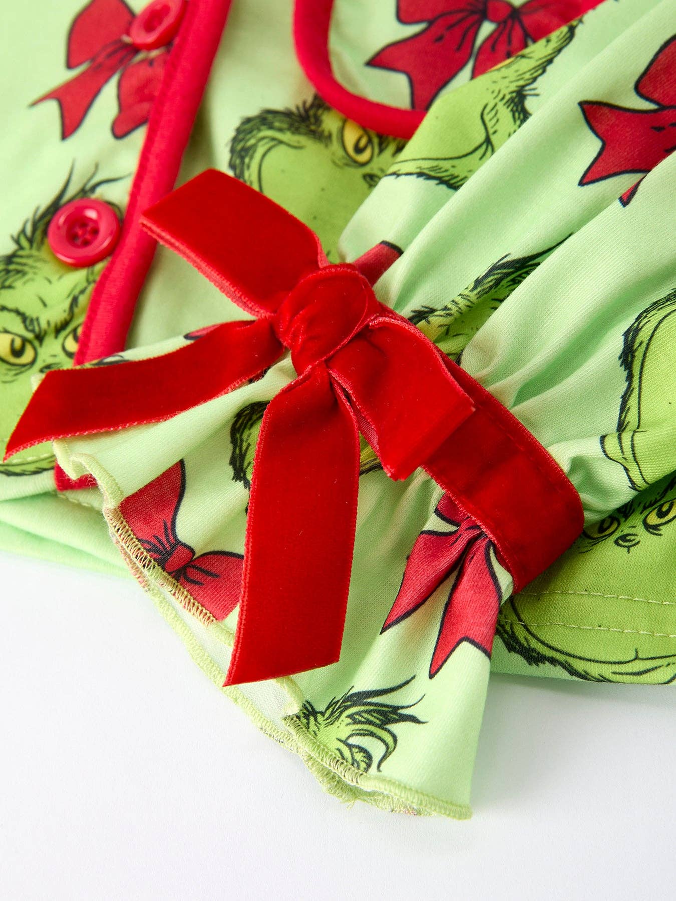 Green fabric with red bows and Grinch design on a white background