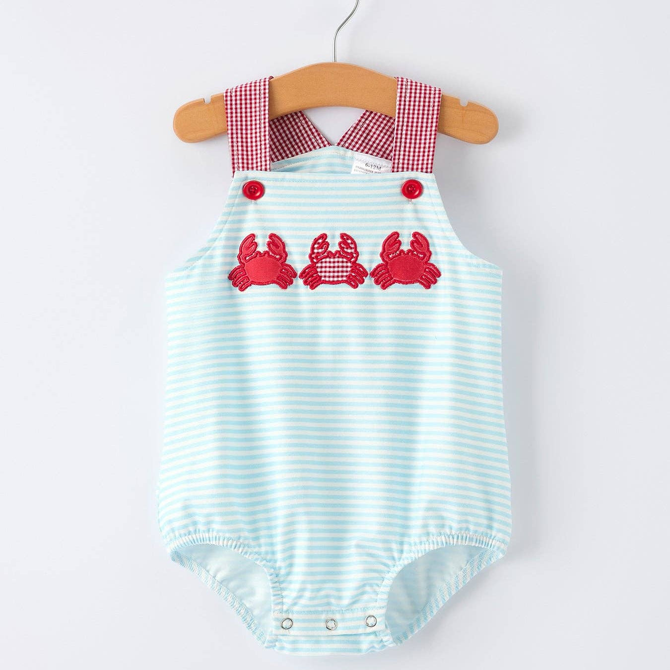 Striped baby romper with red crab design on a hanger against a white background