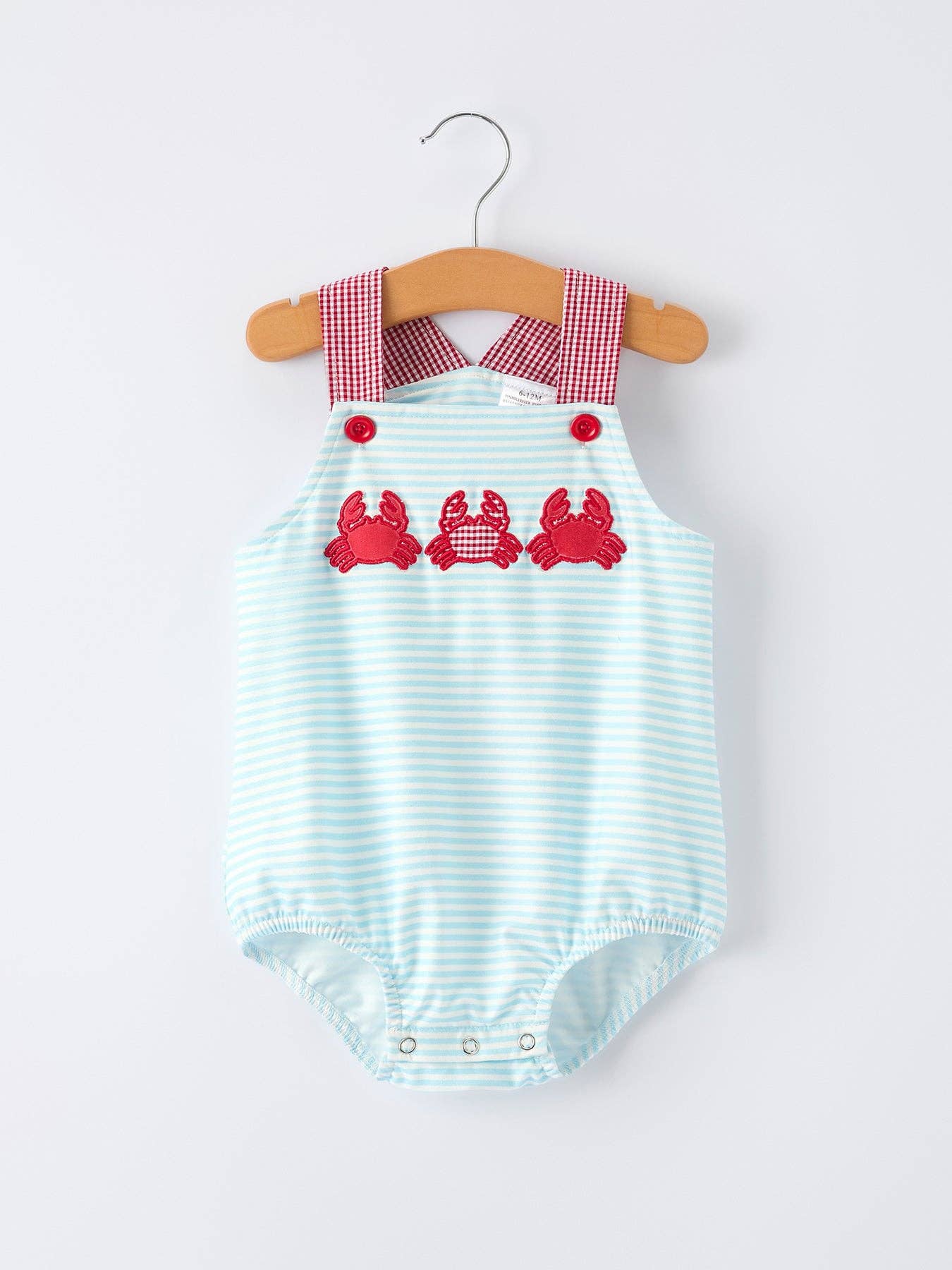 Striped baby romper with red crab design on a hanger against a white background