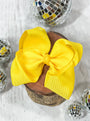 Yellow hair bow on a wooden block with disco balls in the background