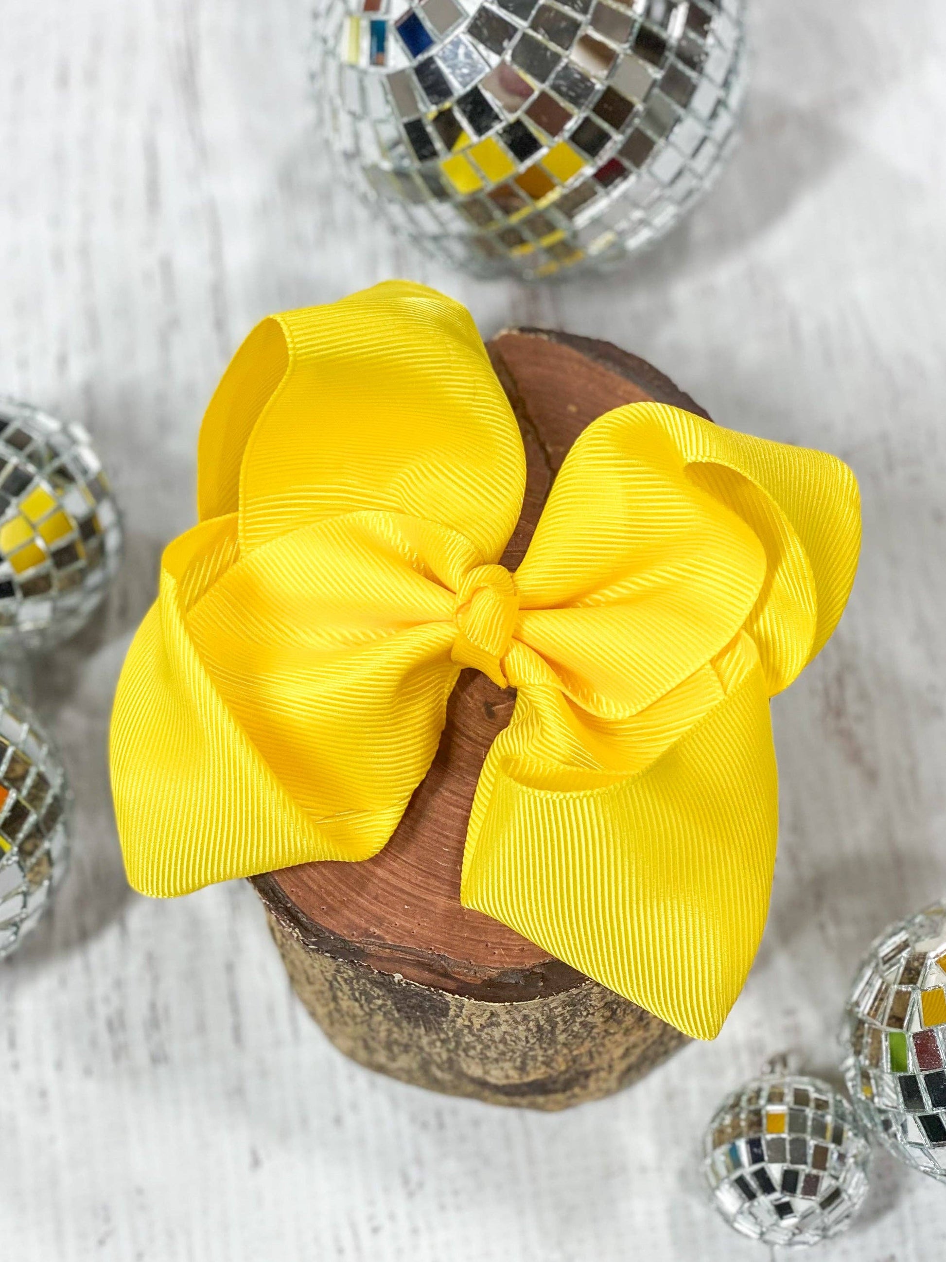 Yellow hair bow on a wooden block with disco balls in the background
