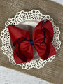 Red hair bow on a decorative white plate with a textured brown background