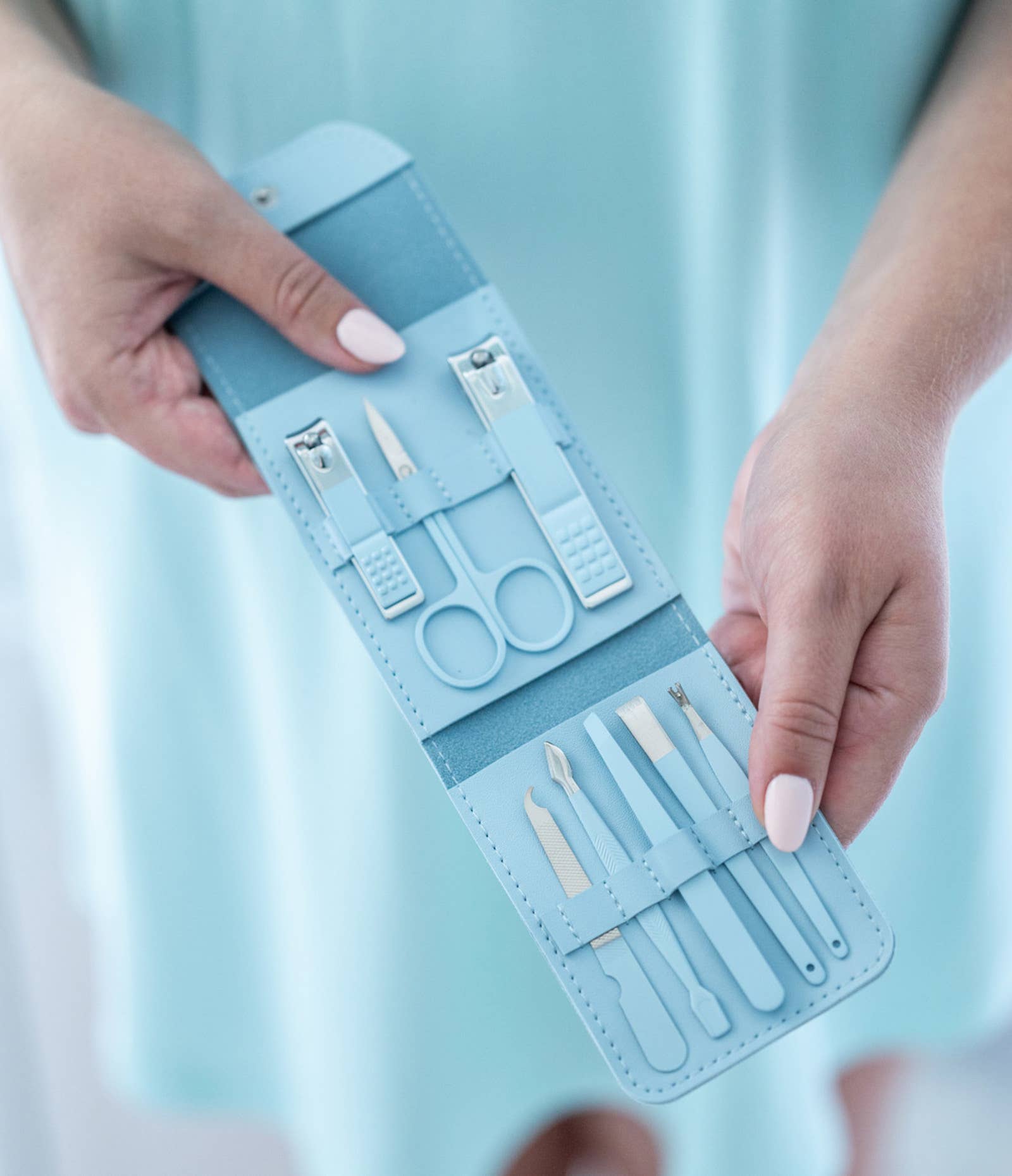 Blue nail care set in a case held by hands against a light blue background