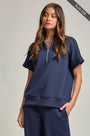 Woman wearing a navy blue outfit with a zipper on a plain background