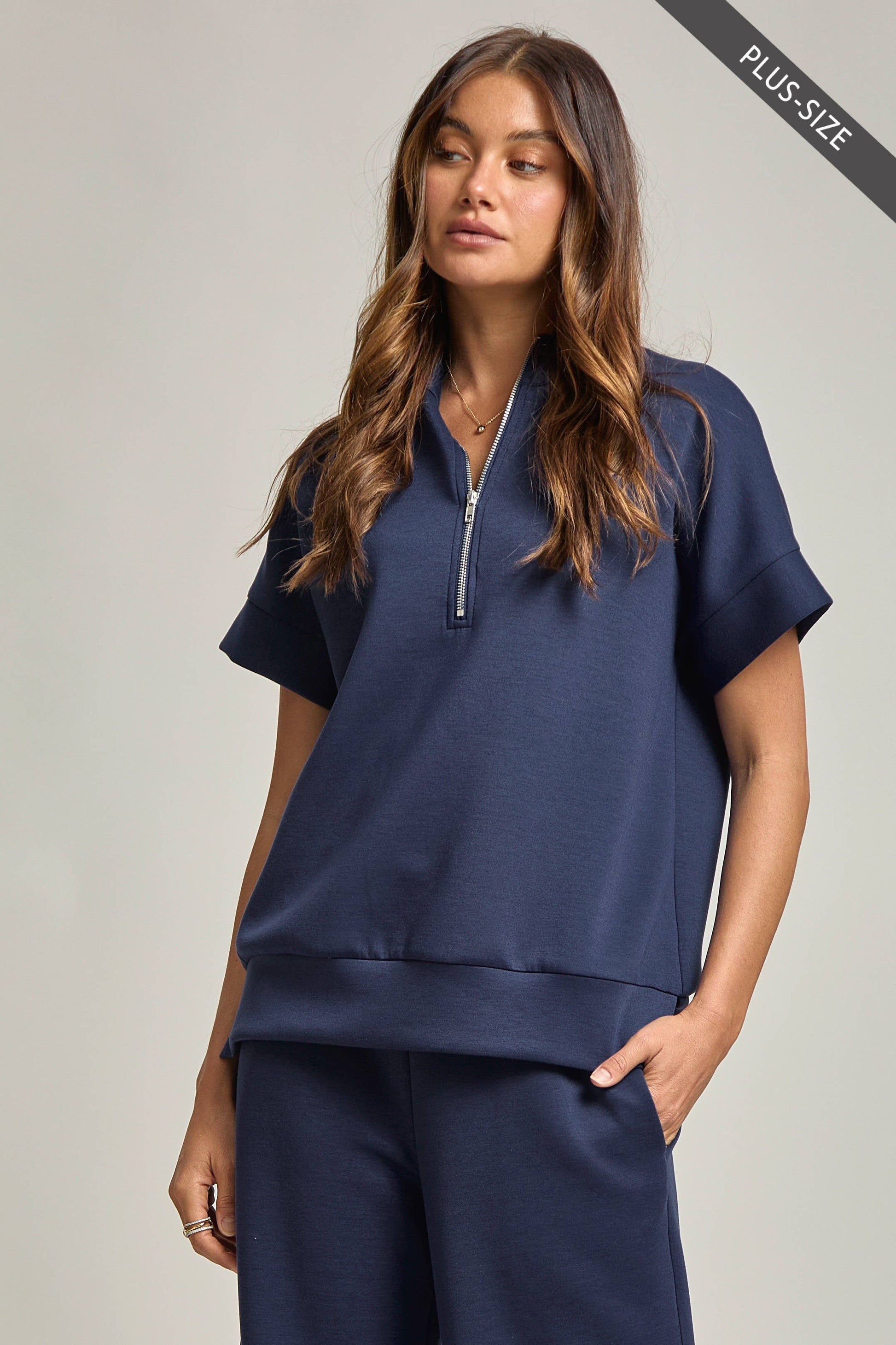Woman wearing a navy blue outfit with a zipper on a plain background