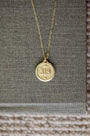 Gold necklace with a round pendant on a textured surface