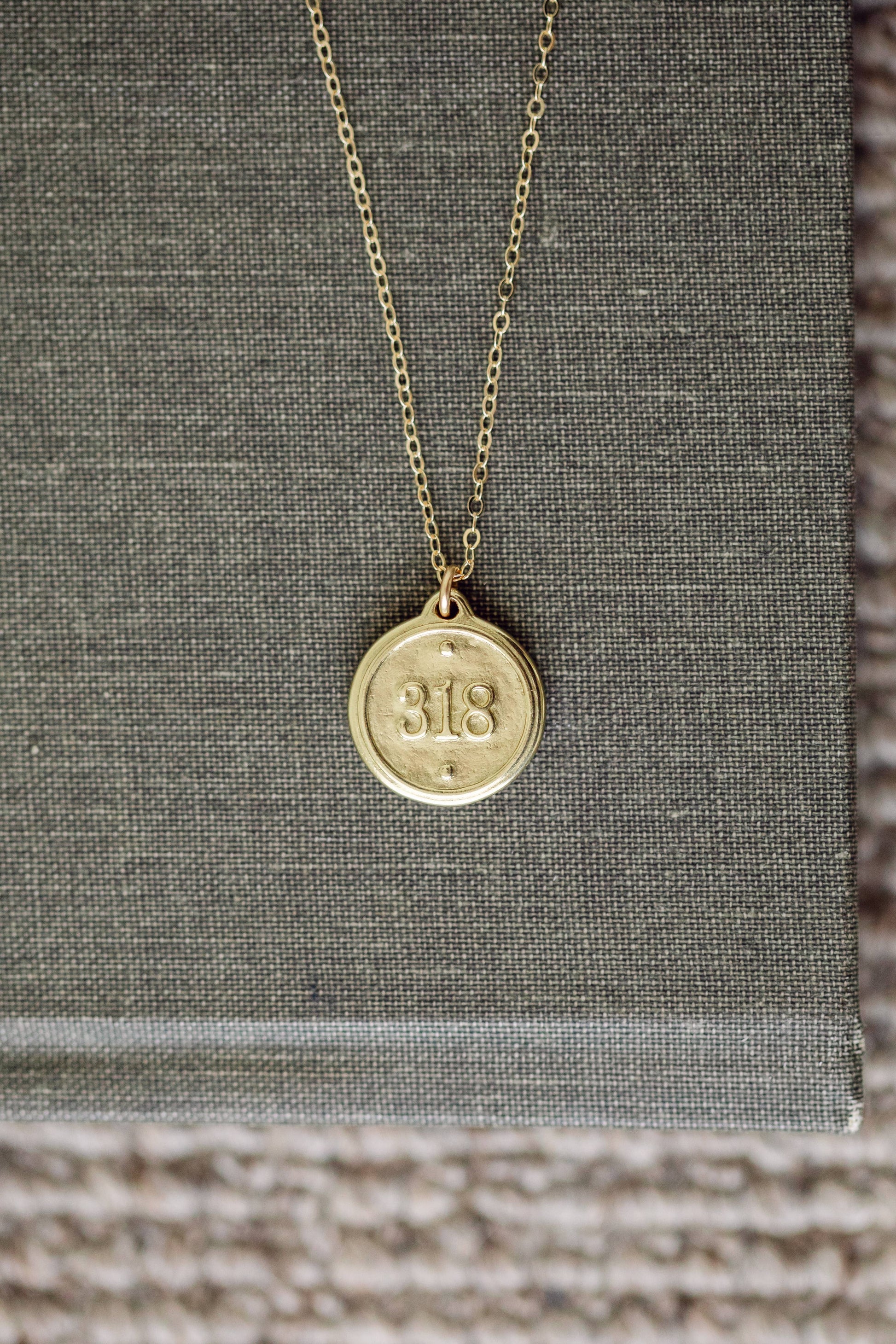 Gold necklace with a round pendant on a textured surface