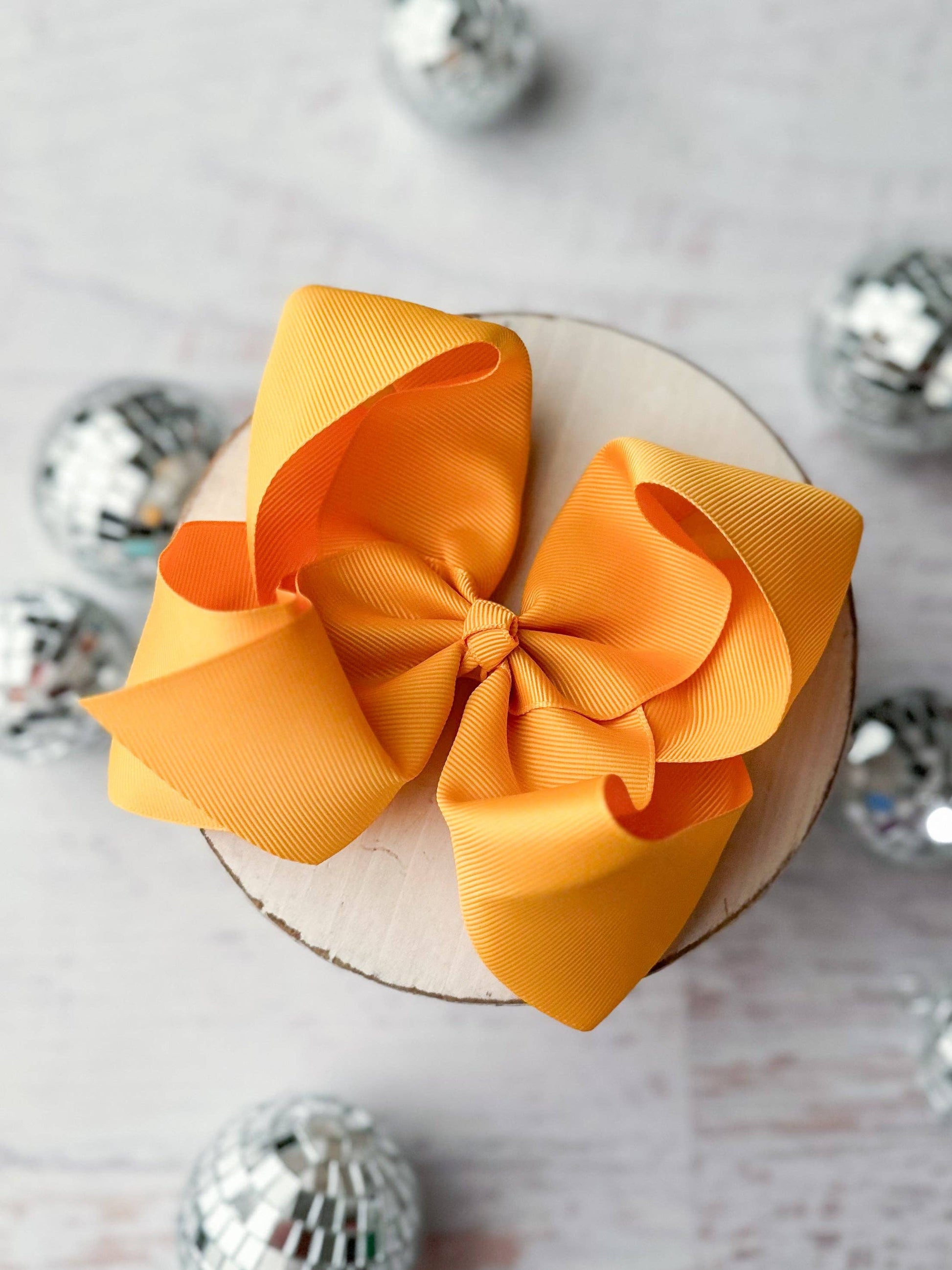 Large yellow bow on a white surface with decorative silver balls around