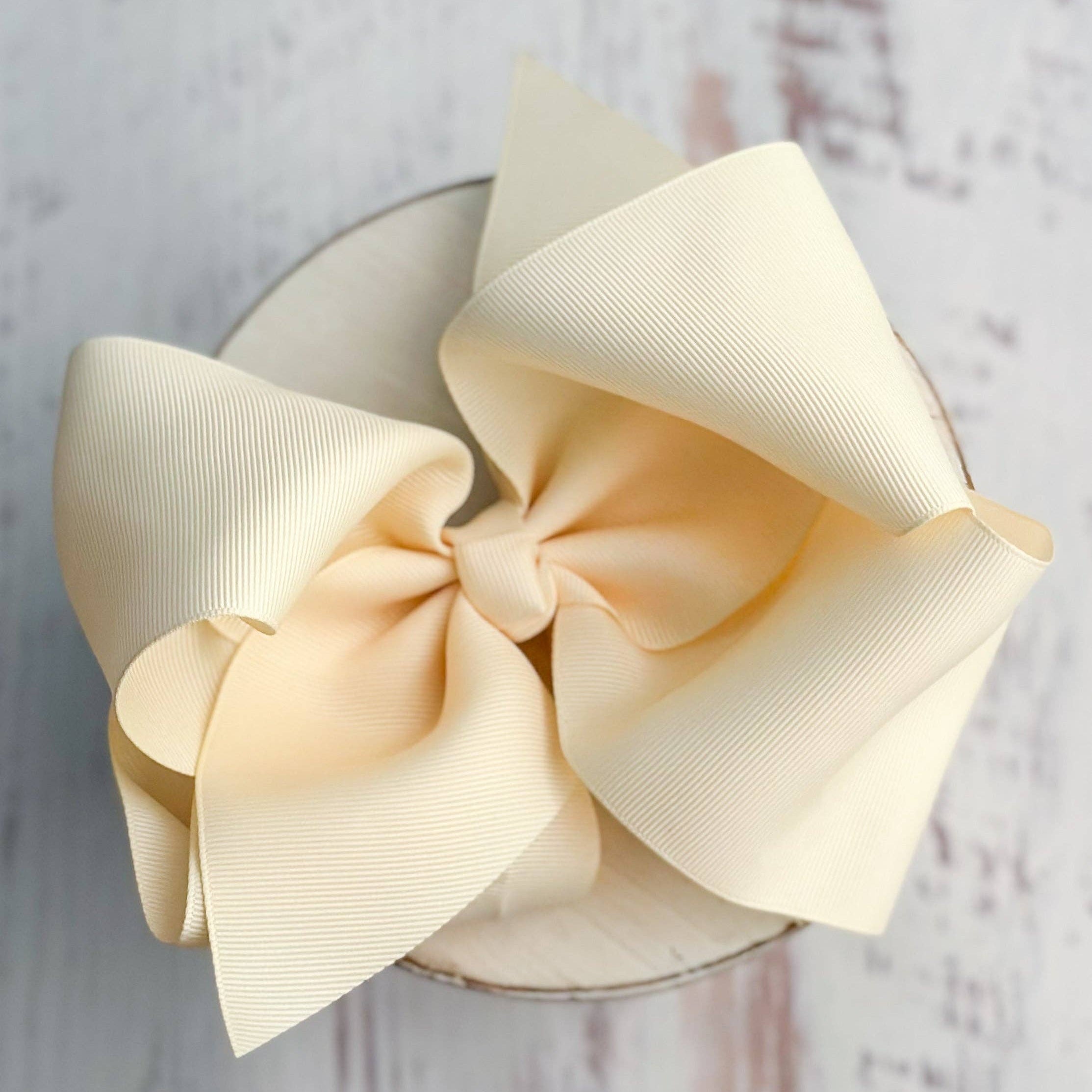 Large cream-colored bow on a wooden surface