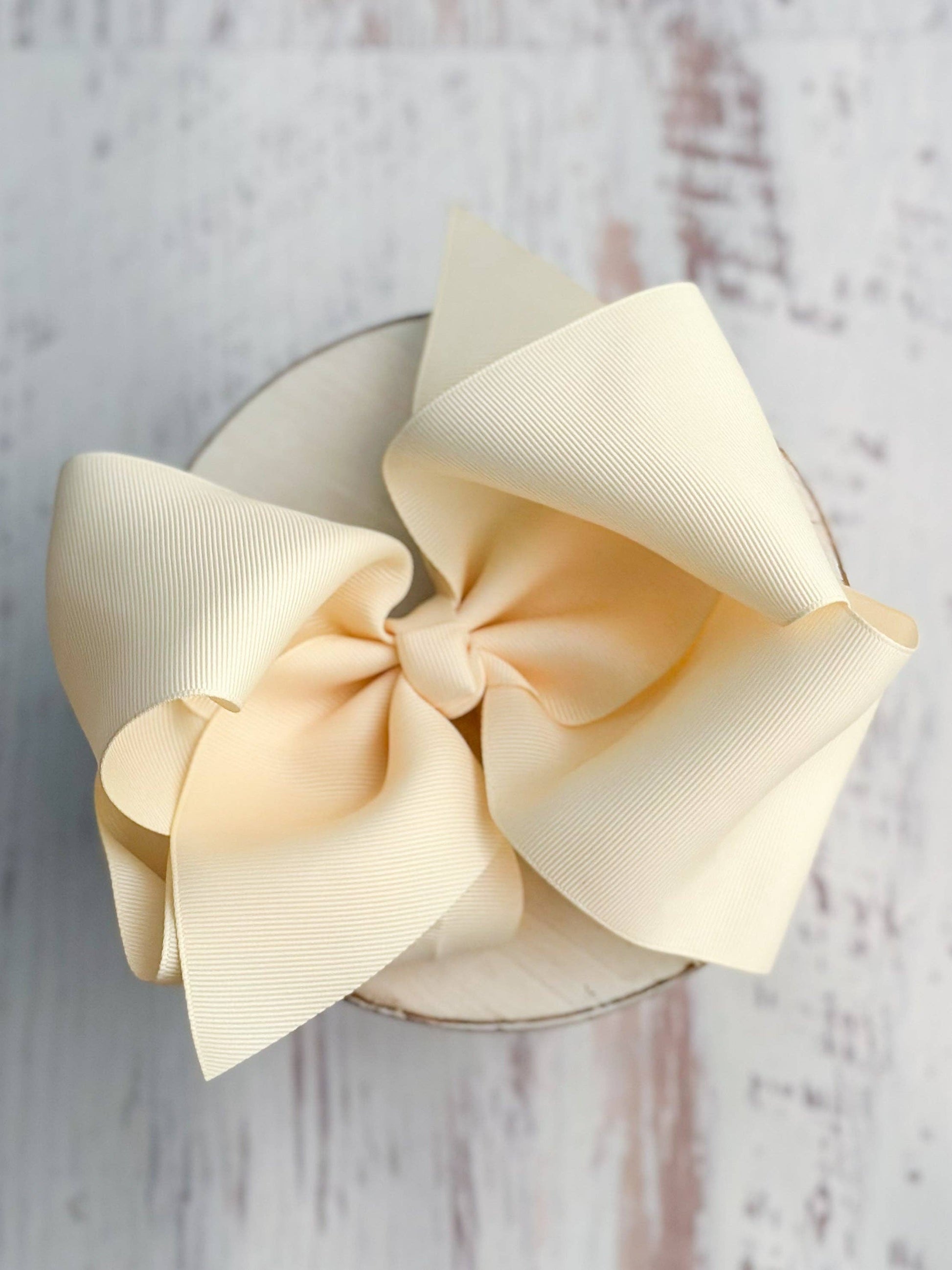 Large cream-colored bow on a wooden surface