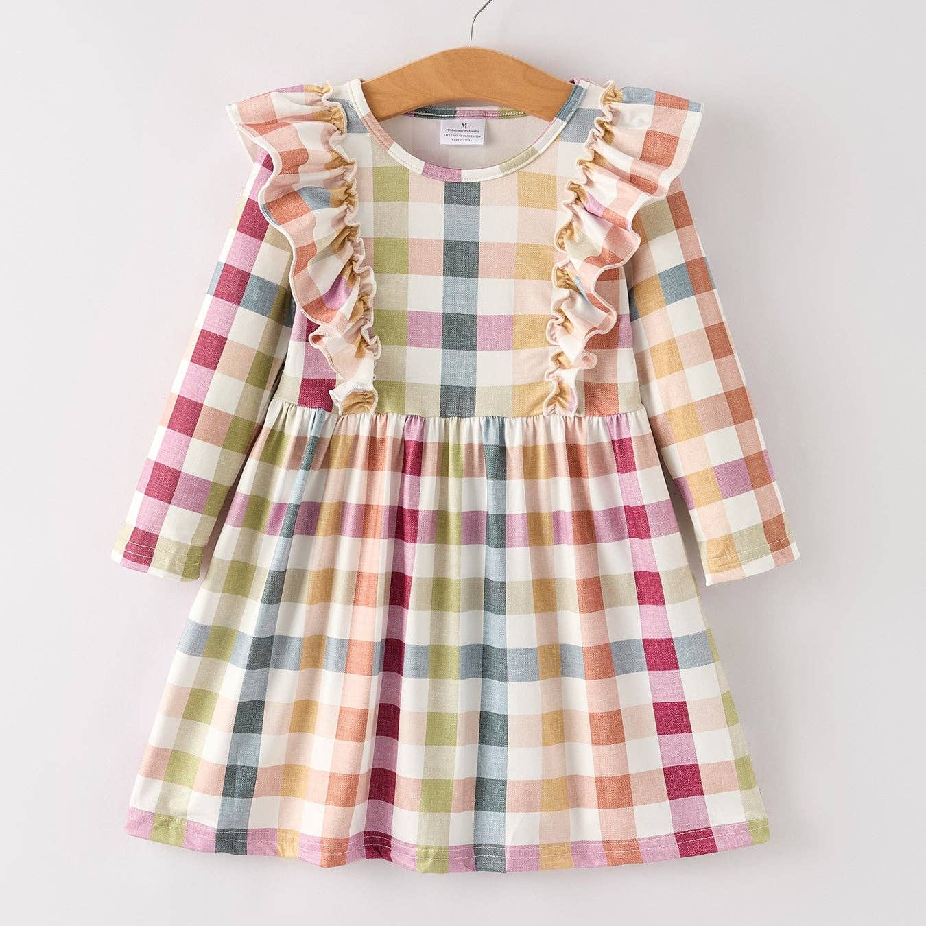 Plaid dress with ruffled sleeves on a hanger against a white background