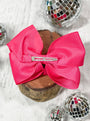 Large pink bow with a clip on a wooden block with disco balls in the background