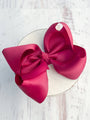 Large pink bow on a white plate with a light wooden background