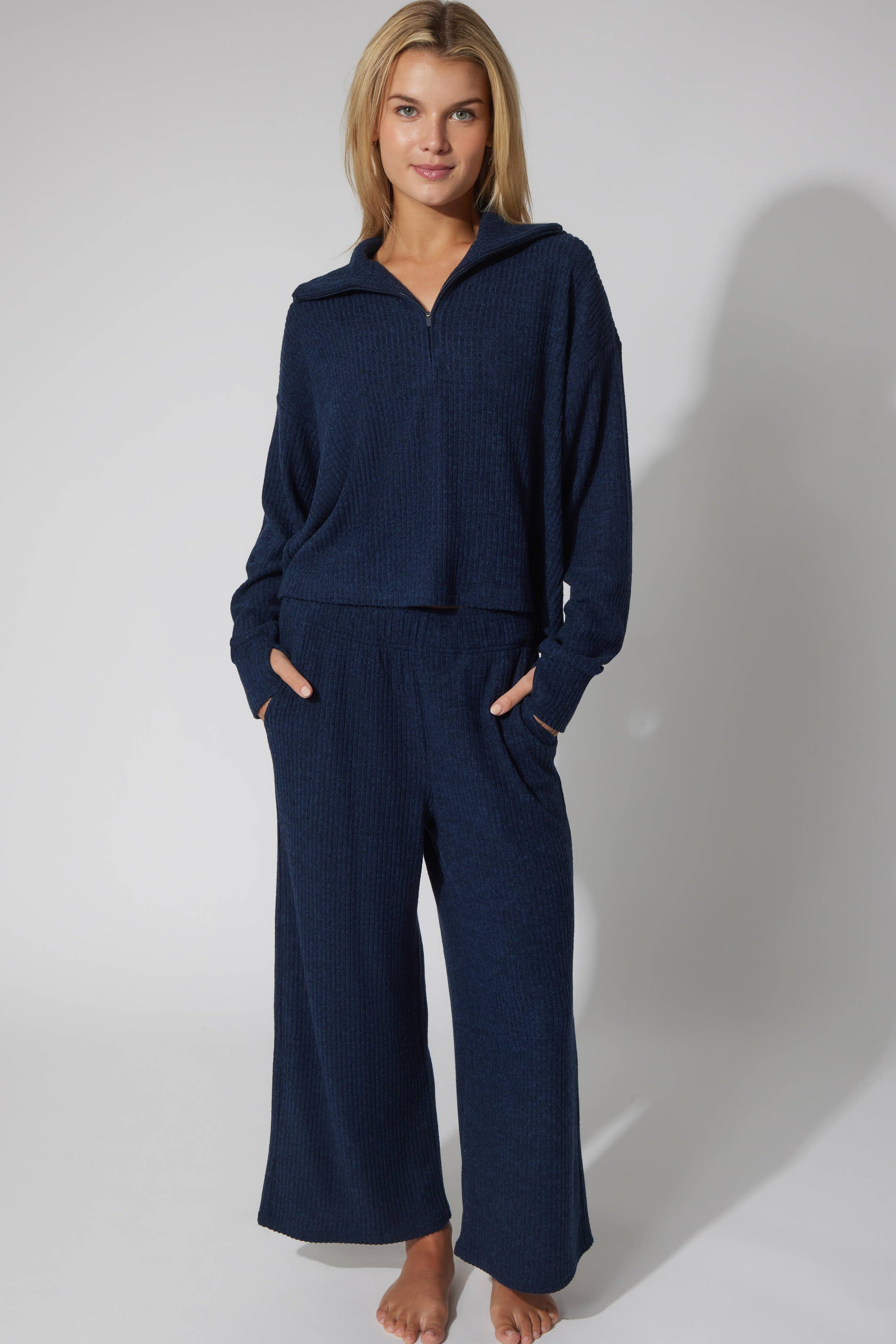 Woman wearing navy blue knit set against a white background