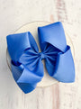 Blue hair bow on a white plate with a light wooden background