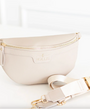 Beige fanny pack with gold zipper and strap on a white background