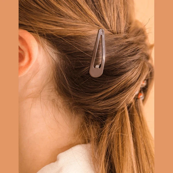 Close-up of a hair clip in a person's hair with a neutral background