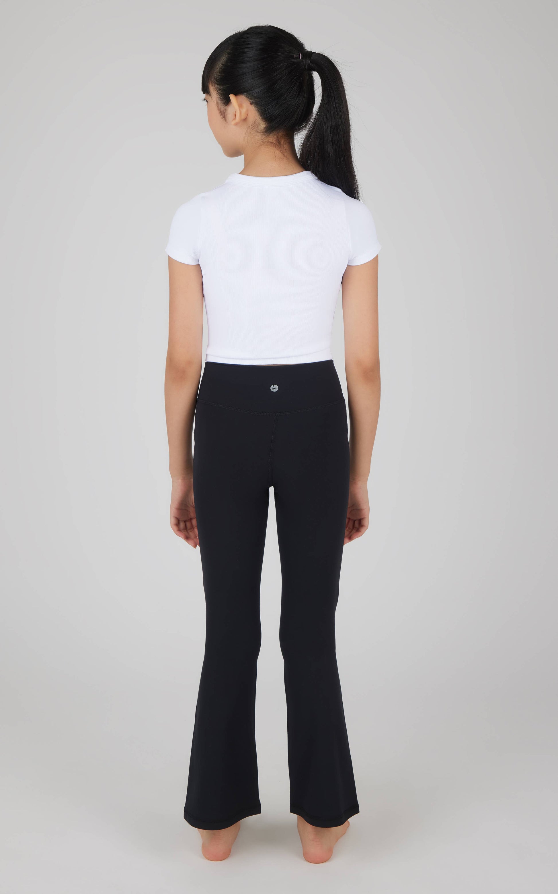 Person wearing a white t-shirt and black flared pants on a plain background