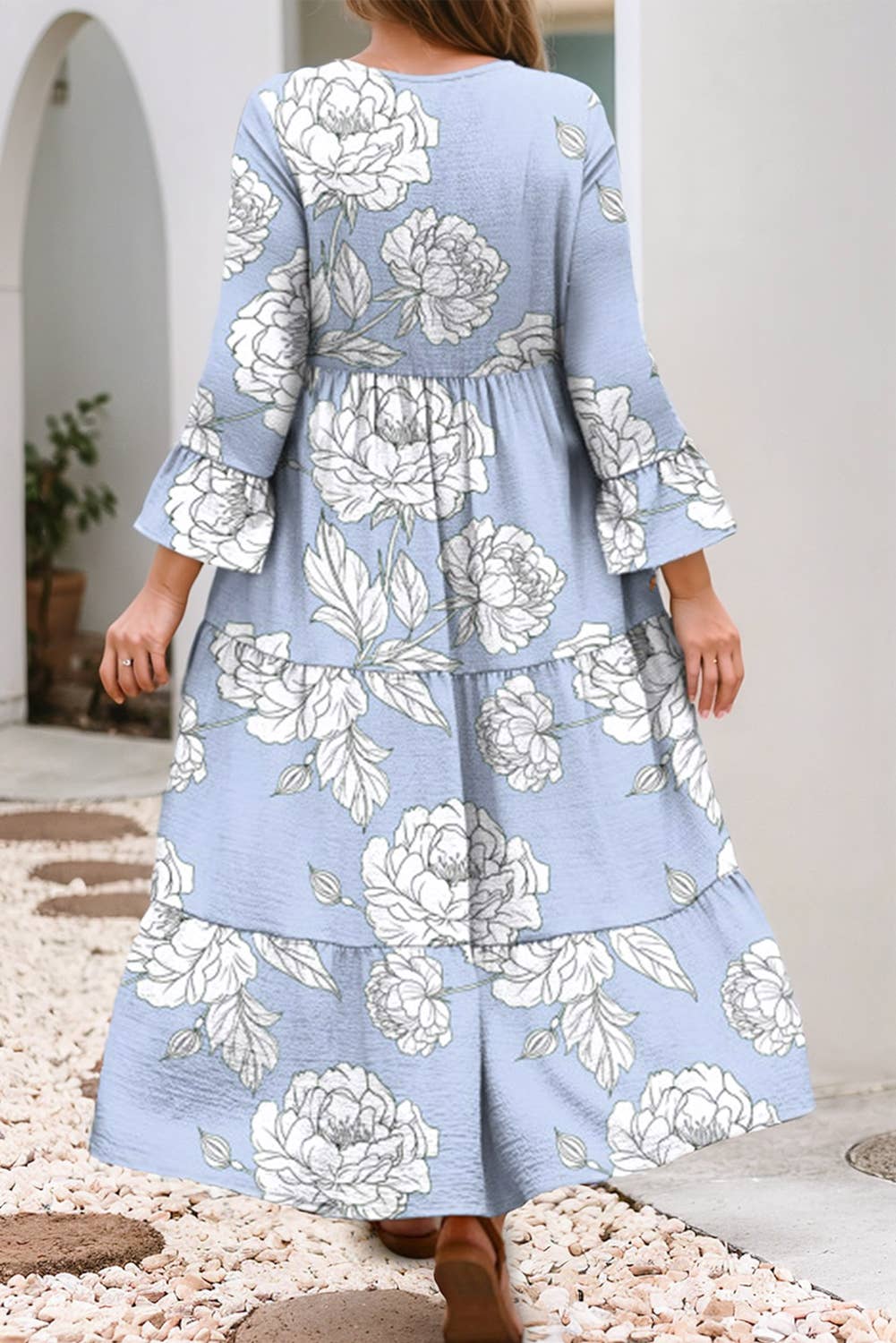 Woman wearing a blue floral dress with ruffled sleeves in an outdoor setting.