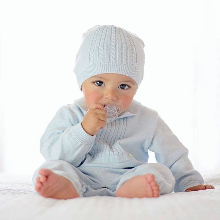 Baby in light blue outfit with matching hat on a white background