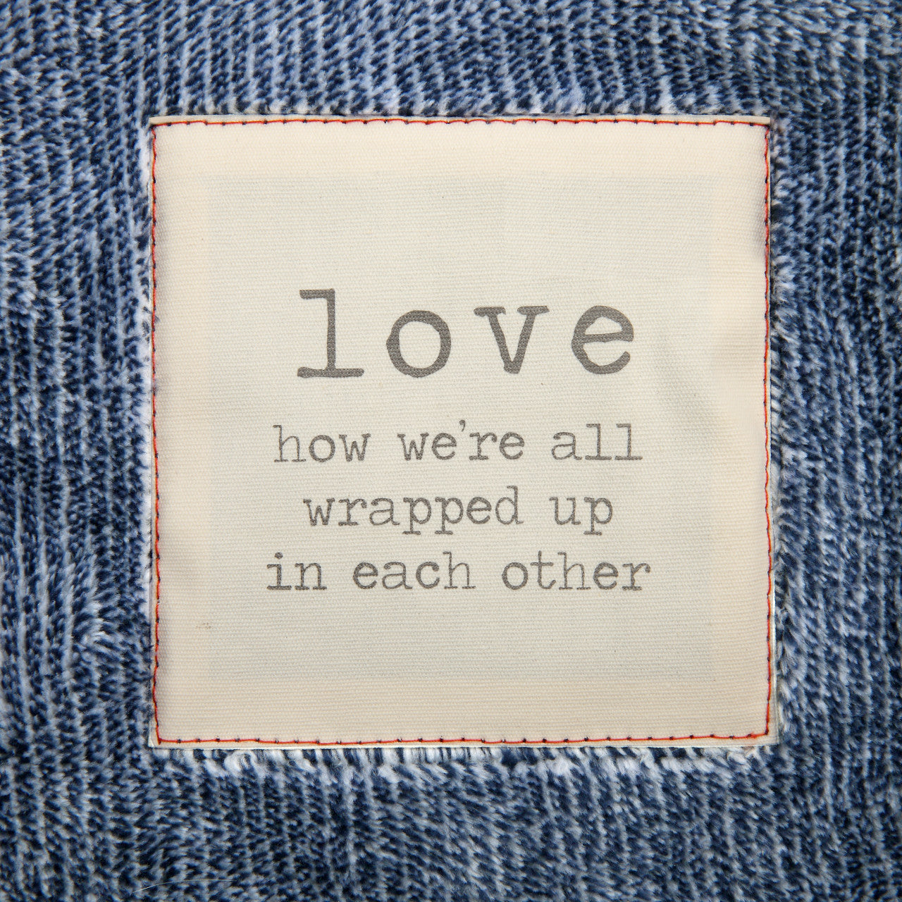 Text on a denim fabric background with the word 'love' and a quote.