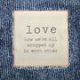 Text on a denim fabric background with the word 'love' and a quote.
