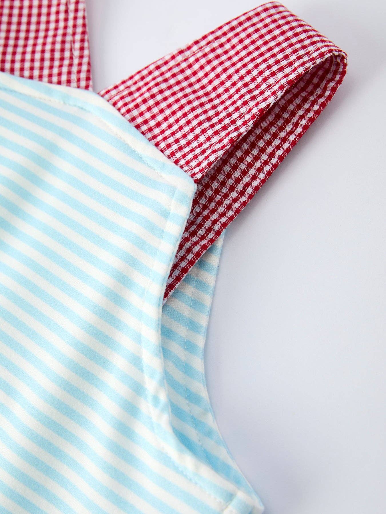 Red and white checkered fabric and blue and white striped fabric on a light gray background
