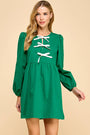 Green dress with white lace-up details worn by a model on a beige background