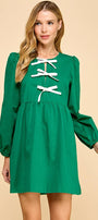 Green dress with white lace-up details worn by a model on a beige background