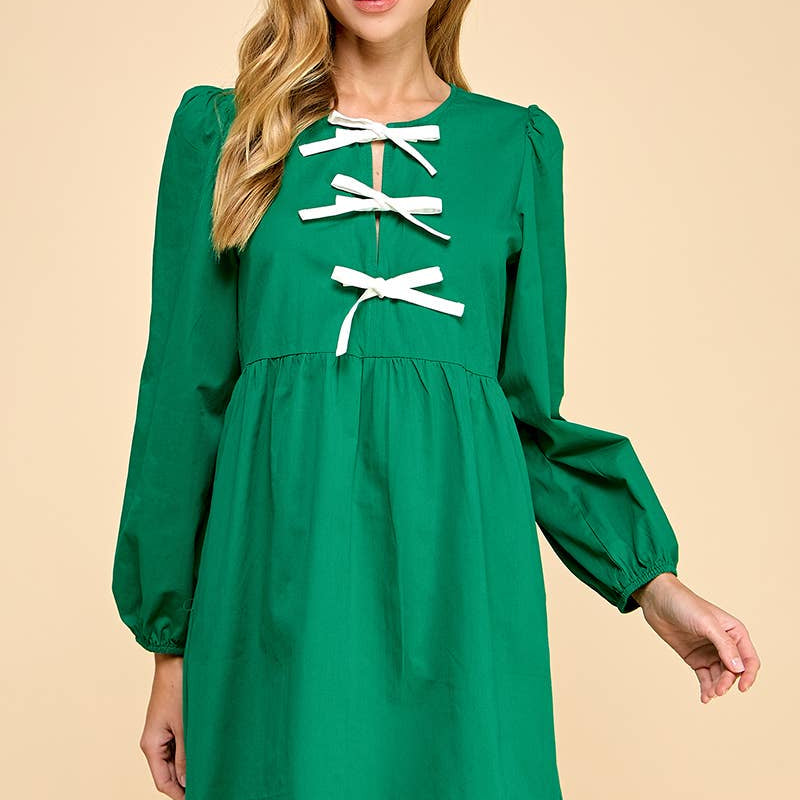Green dress with white lace-up details worn by a model on a beige background