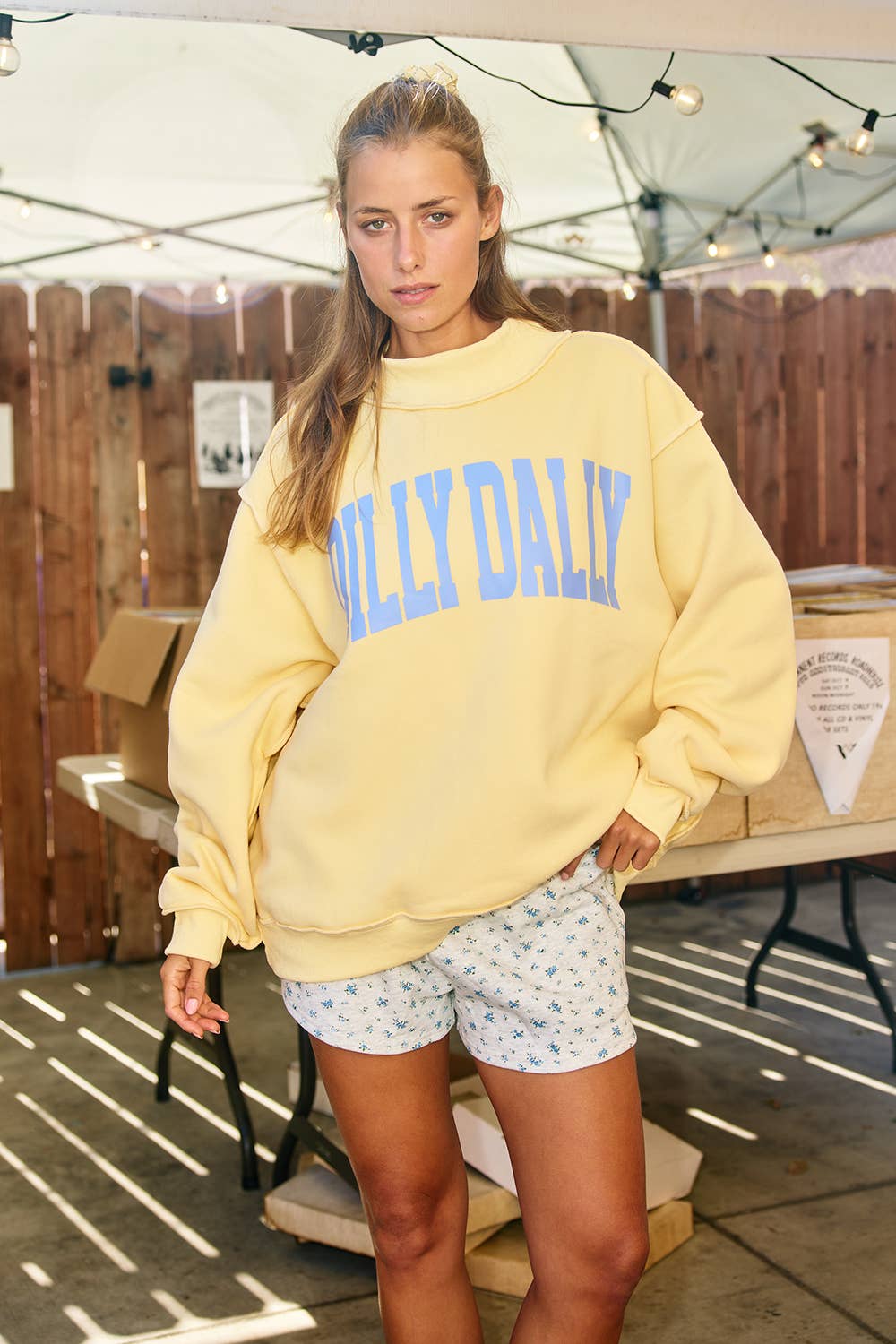 Woman wearing a yellow sweatshirt with 'Hilly Daily' text in an outdoor setting.