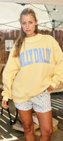 Woman wearing a yellow sweatshirt with 'Hilly Daily' text in an outdoor setting.