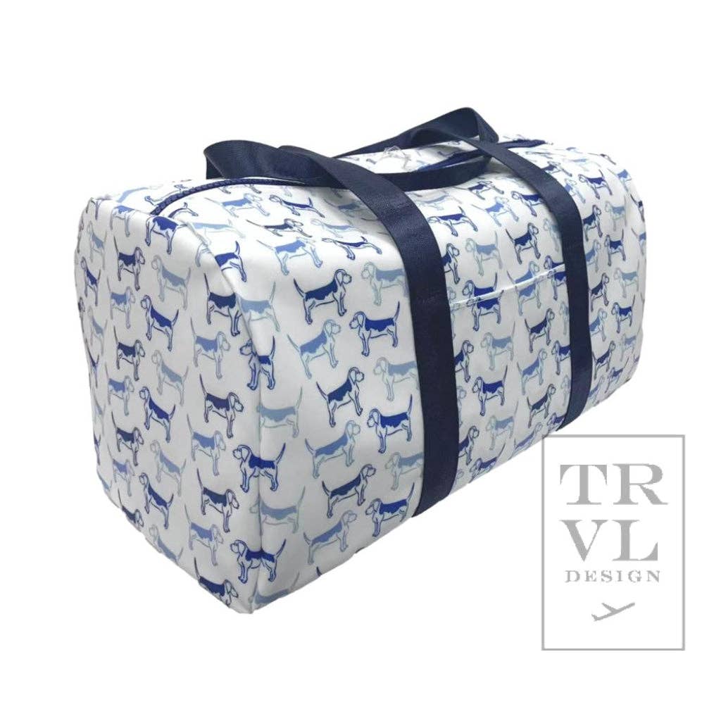 Travel bag with blue dog pattern and black straps on a white background, featuring the TRVL Design logo.