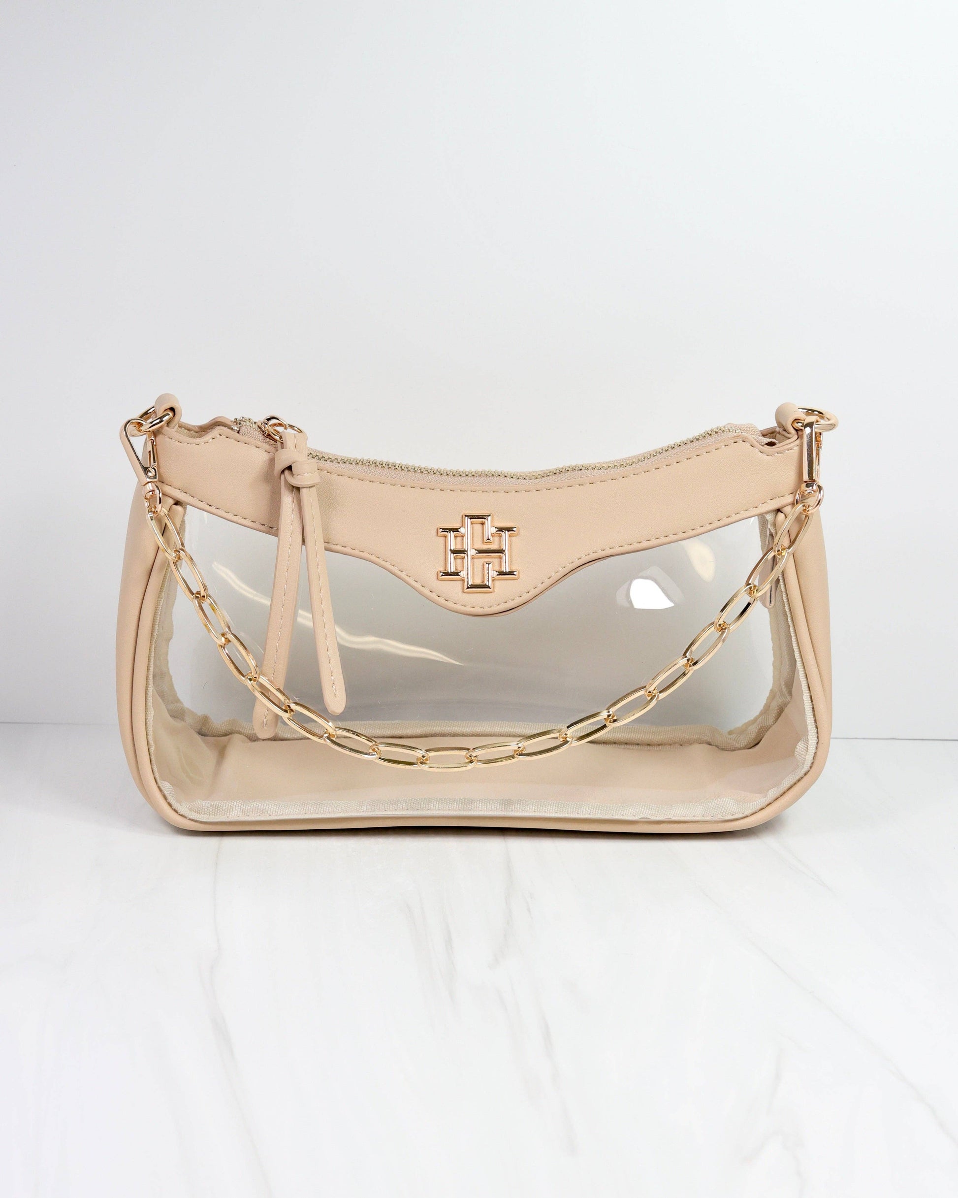 Beige handbag with clear section and gold chain strap on a white background