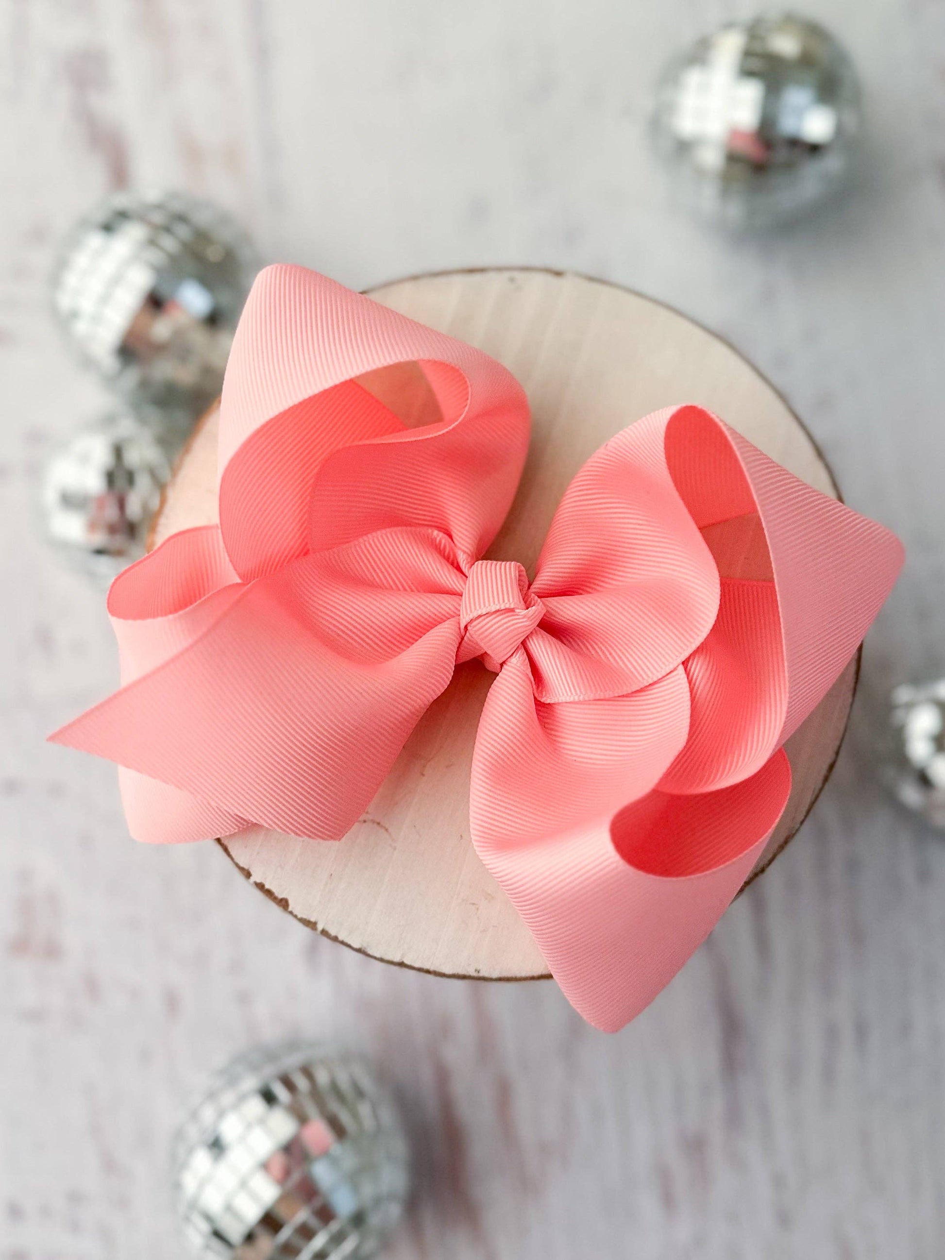 Large pink bow on a wooden block with metallic objects around