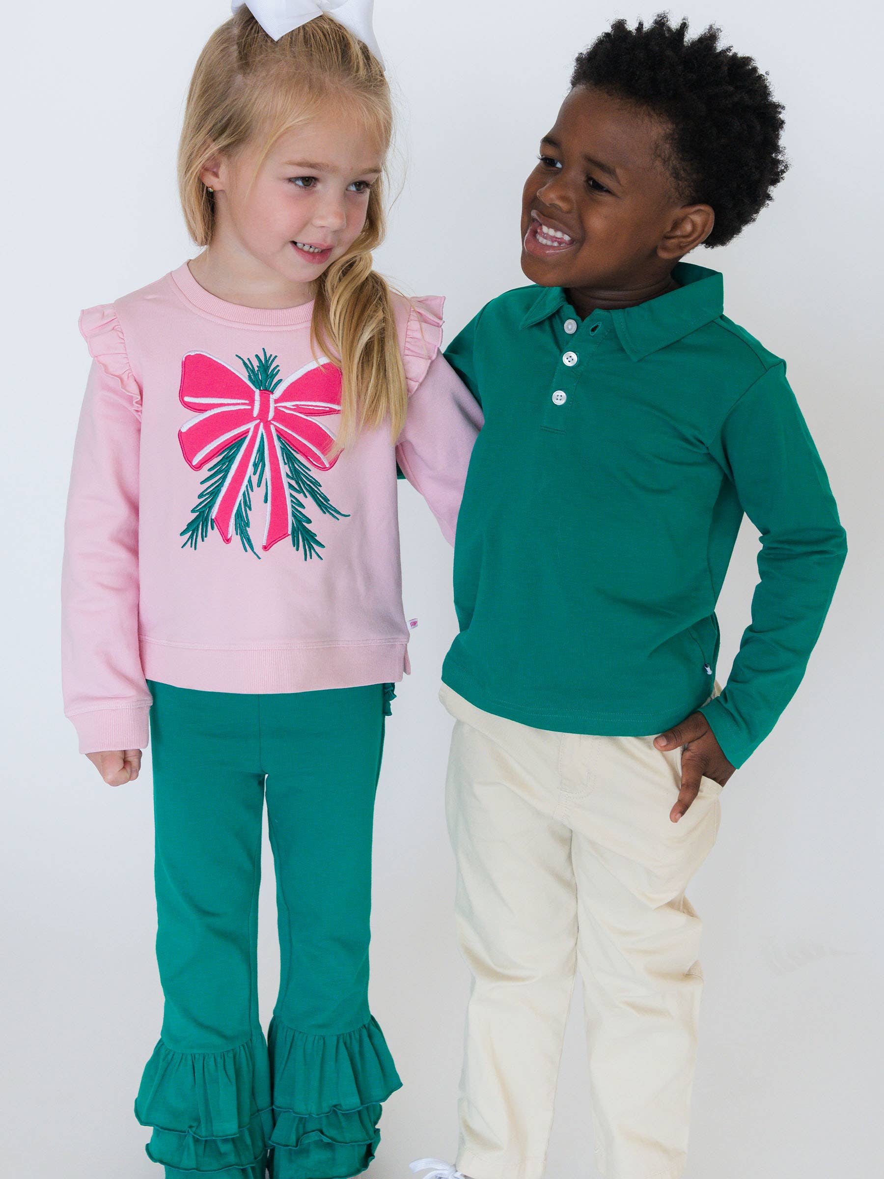 Two children, a girl and a boy, wearing matching outfits with pink and green colors.