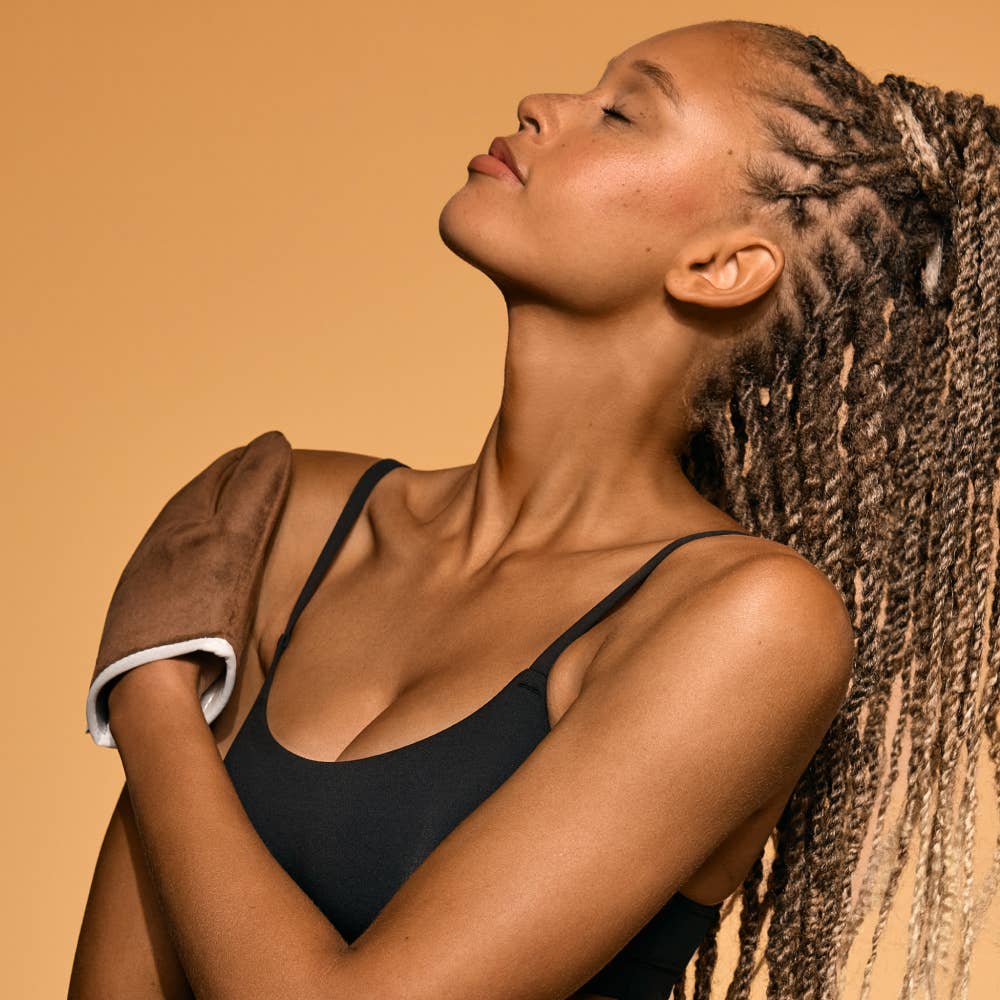 Woman with braided hair wearing a black bikini against a beige background